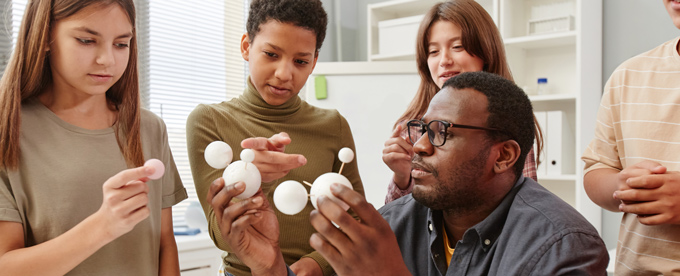 science teacher showing young students model planets